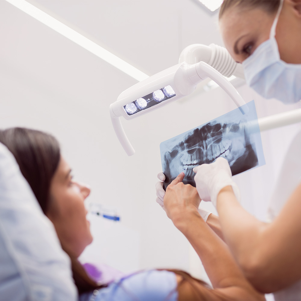 Odontóloga del Hospital Recoletas Salud explicando una radiografía dental antes de una endodoncia en Cádiz.