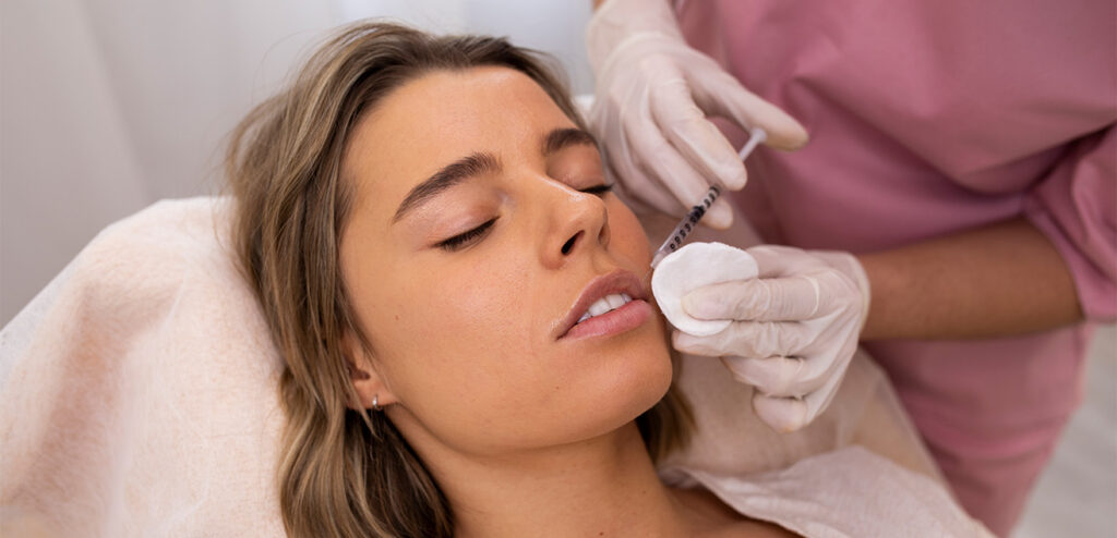 Paciente recibiendo un tratamiento facial con ácido hialurónico en consulta médica estética.