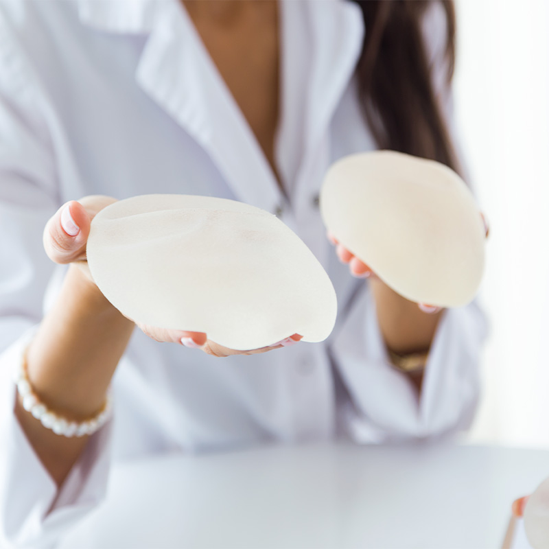 Profesional sanitaria mostrando implantes mamarios de silicona para una cirugía de aumento de pecho.