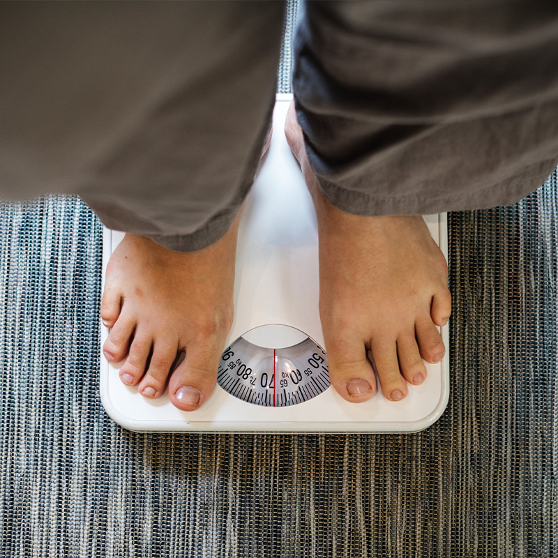 Persona de pie sobre una báscula para controlar su peso durante un tratamiento de obesidad.