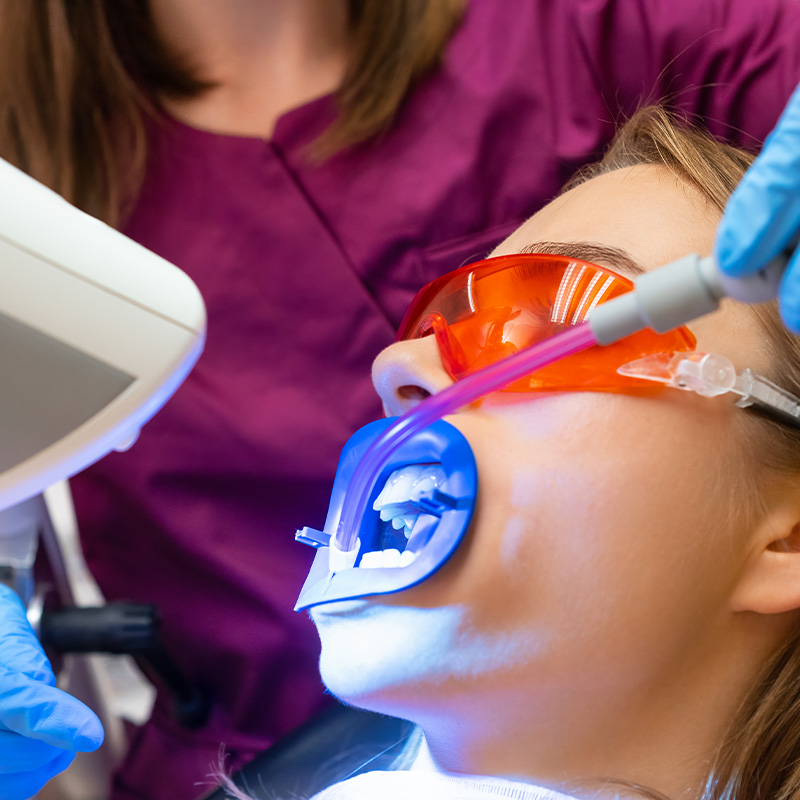Odontóloga aplicando tratamiento de blanqueamiento dental con tecnología avanzada en Hospital López Cano.