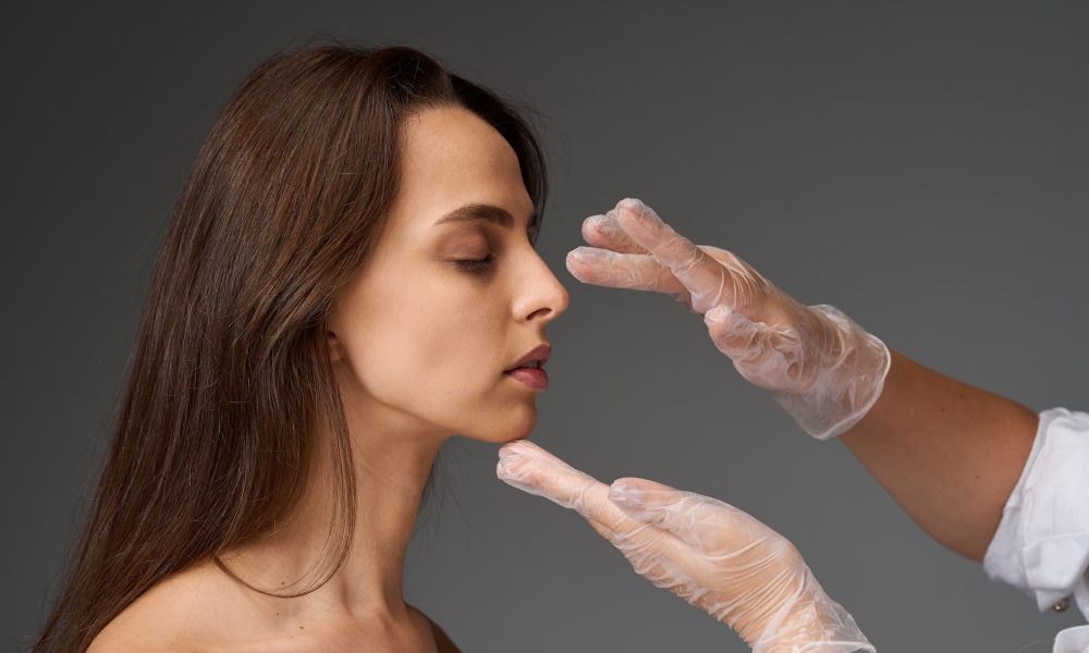 Rhinoplasty and facial proportion correction concept for a surgical nose reshaping procedure. Surgeon palpating nasal septum of girl for rhinoplasty procedure.